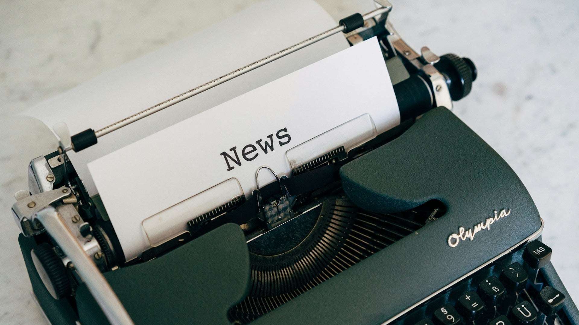 Olympia typewriter with 'News' paper on a light background